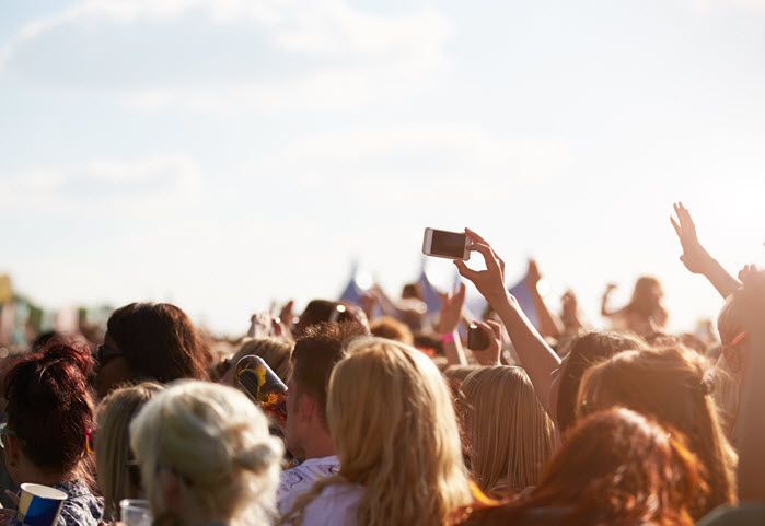 A person holds their cell phone above the crowd at an event