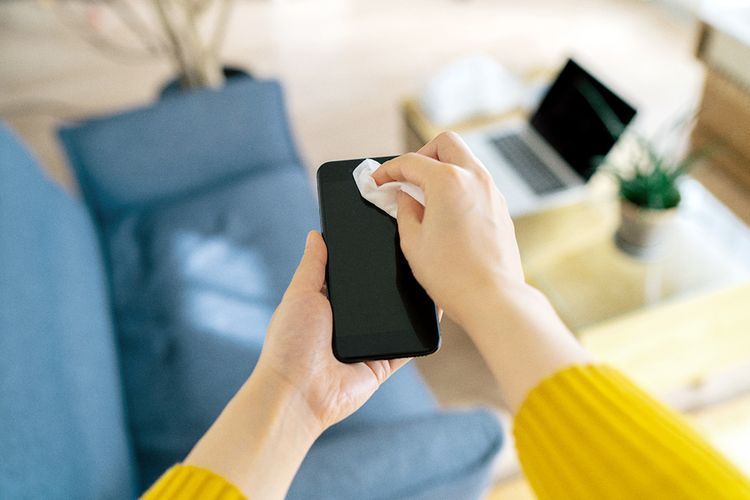 Person cleaning their cell phone screen with a cloth