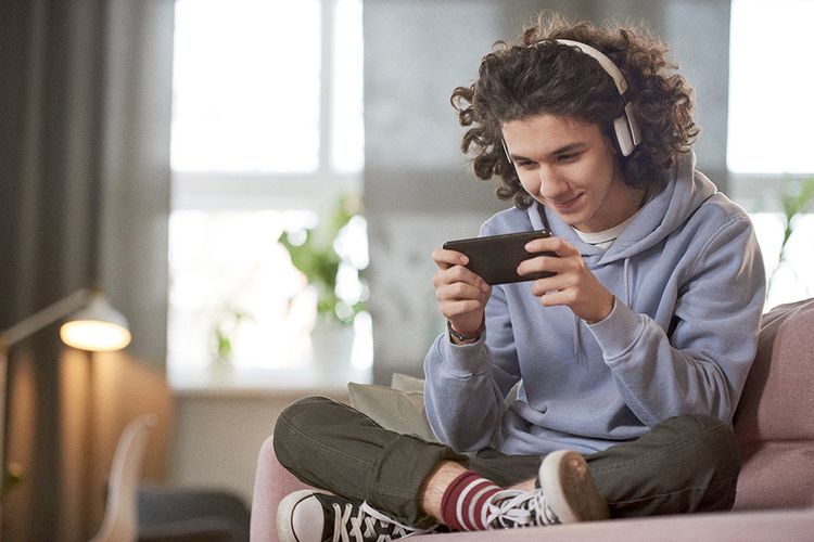 Teenager looking at his phone screen, wearing headphones