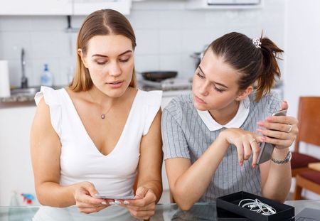 Two women transfer data from one phone to another